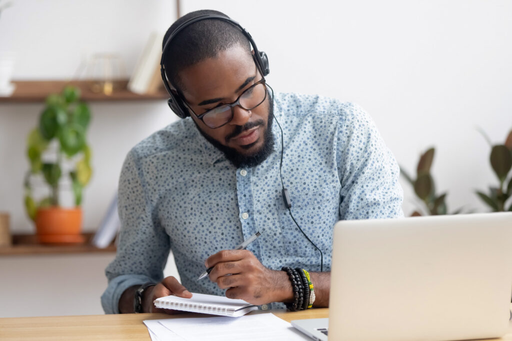 man wearing headphones while writing notes