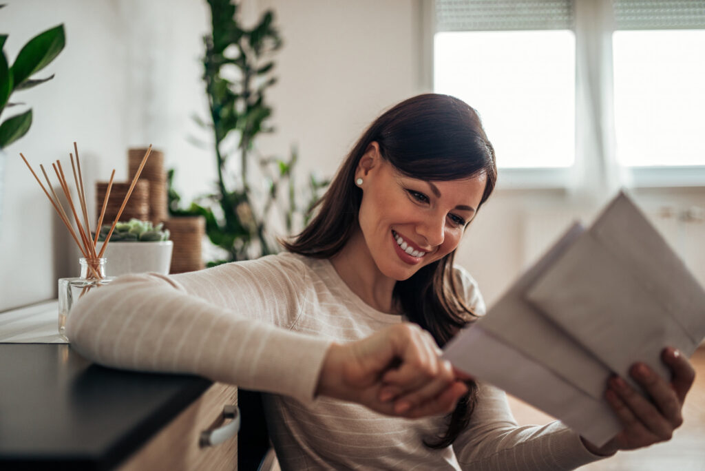 smiling woman reading mail comfortable at home