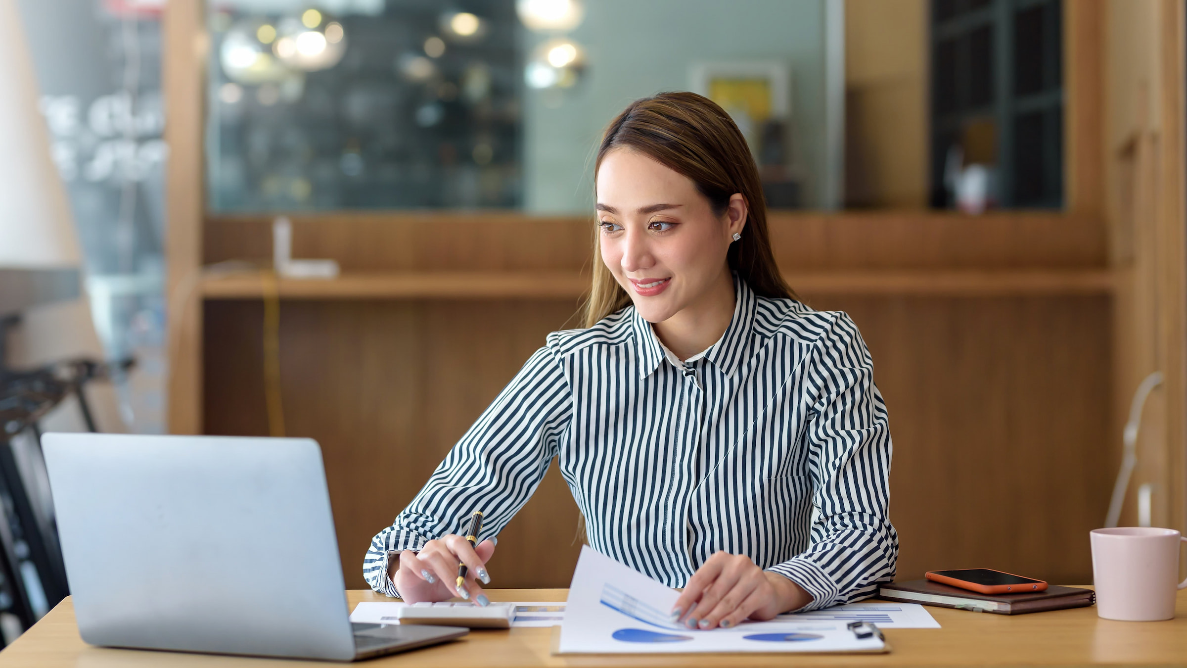 woman in striped shirt doing work laptop coffee cafe