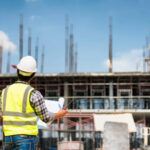 construction worker blueprints building scaffolds yellow vest