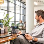 man at desktop using poly telecoms setup