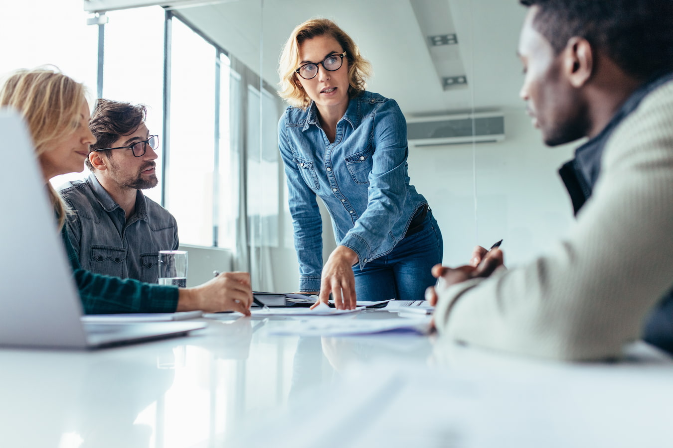 woman leading team in white meeting room table