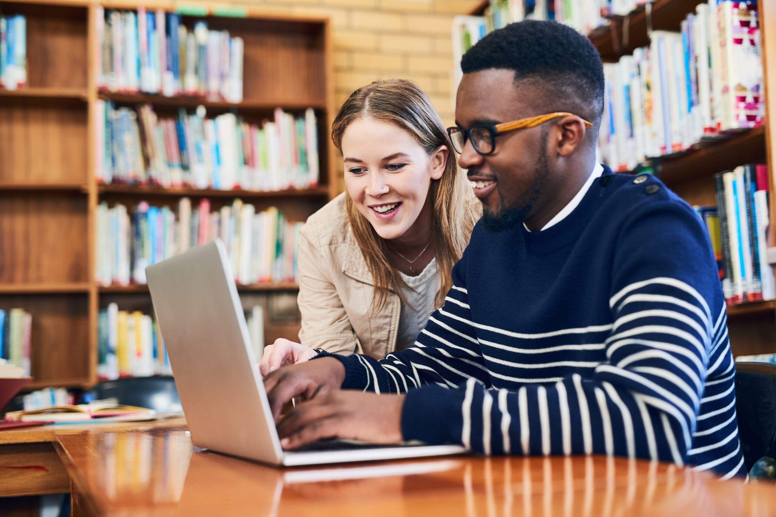 Studierende, die in einer Bibliothek an einem Laptop arbeiten